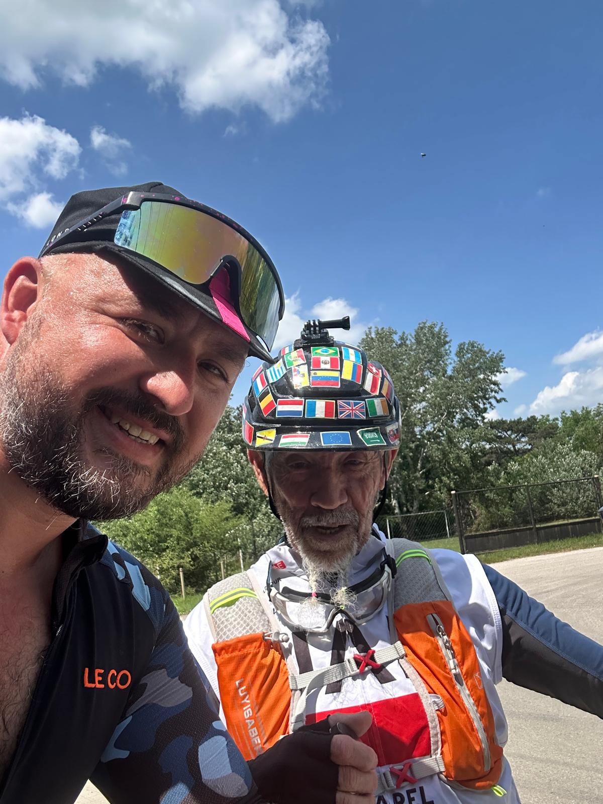 Roadside selfie with a fellow long-distance cyclist whose helmet is covered in country flags