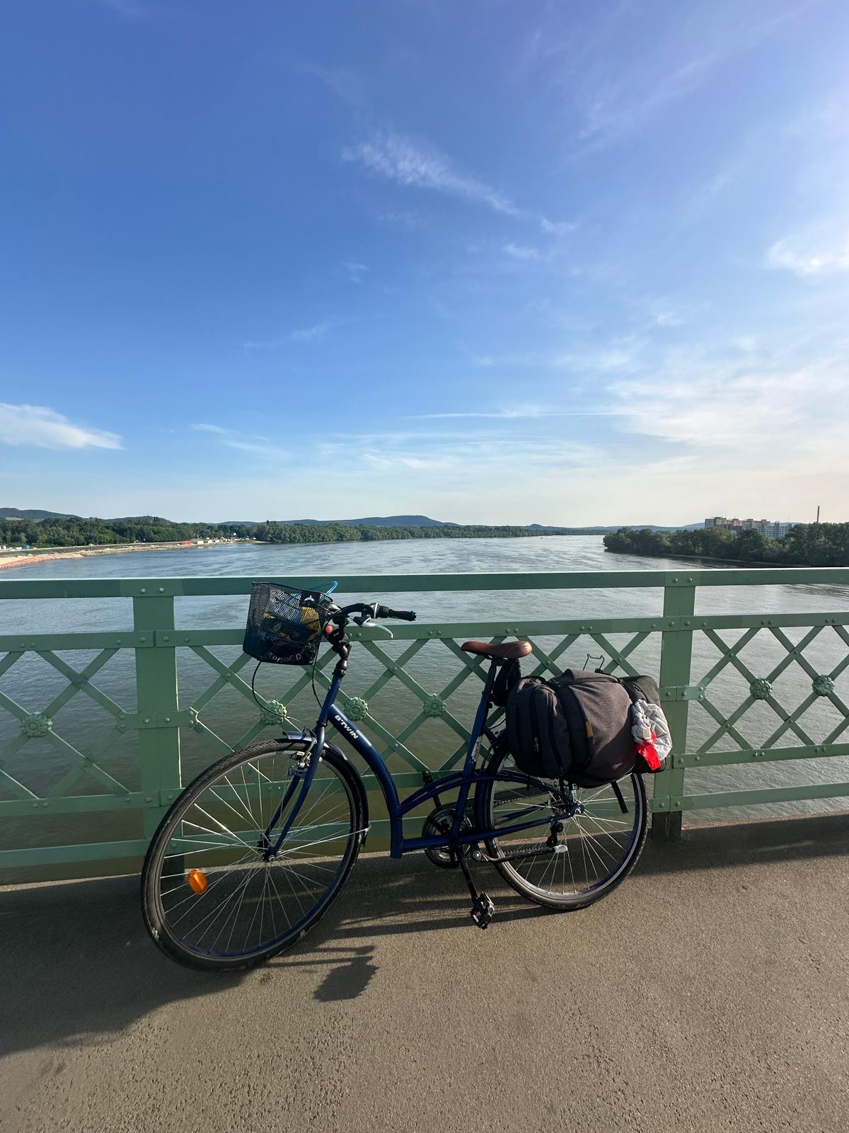 The loaded bike leaning on a green steel bridge railing over the Danube