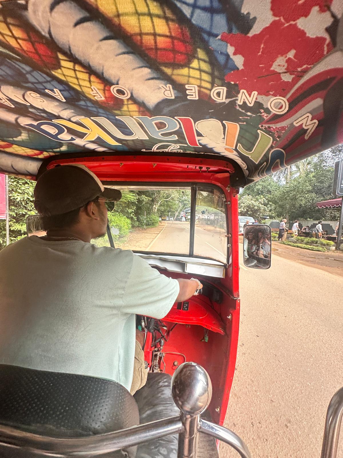 Riding in the back of a red tuktuk with a Sri Lanka Wonder of Asia canopy