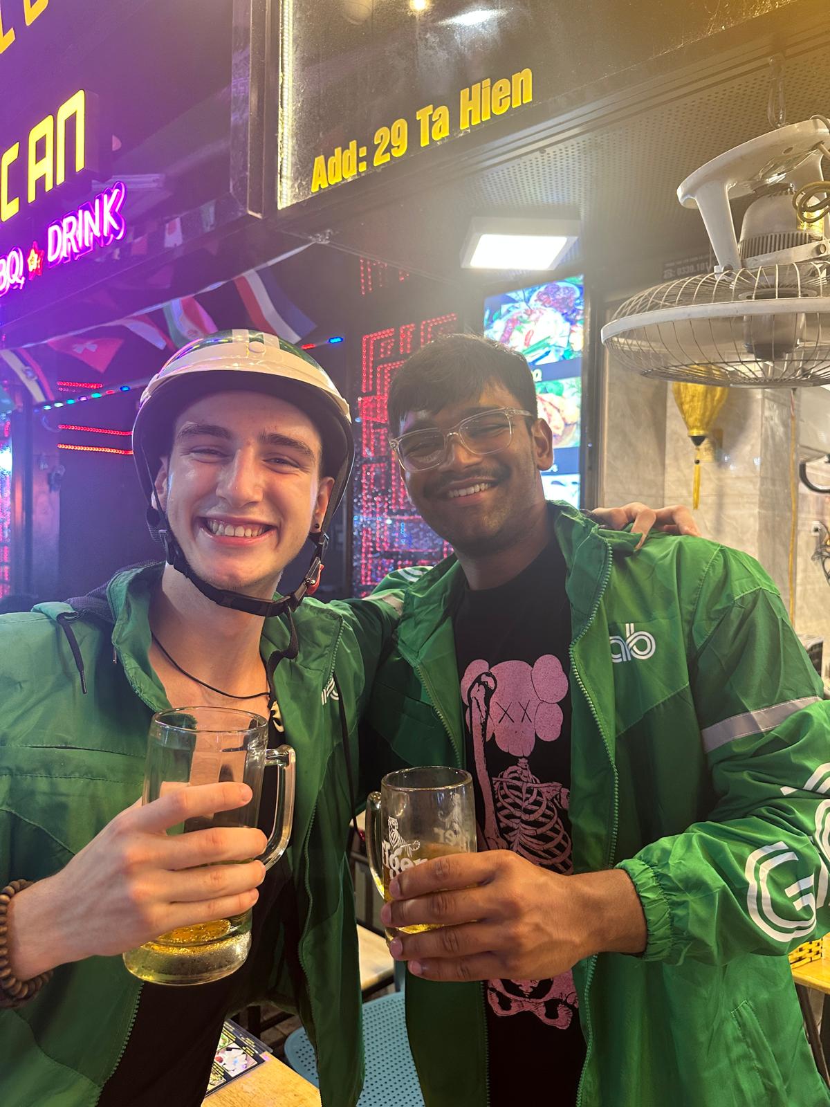 The crew in green Grab jackets with drinks at a Ta Hien street bar in Hanoi